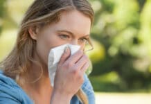 Rinita alergica femeie suflandu-si nasul in parc